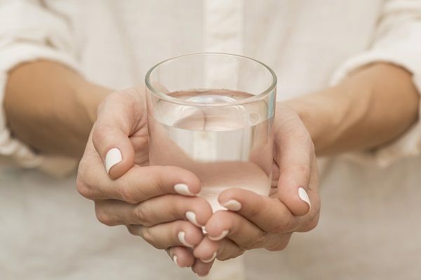 Mujer sosteniendo vaso de agua con las manos